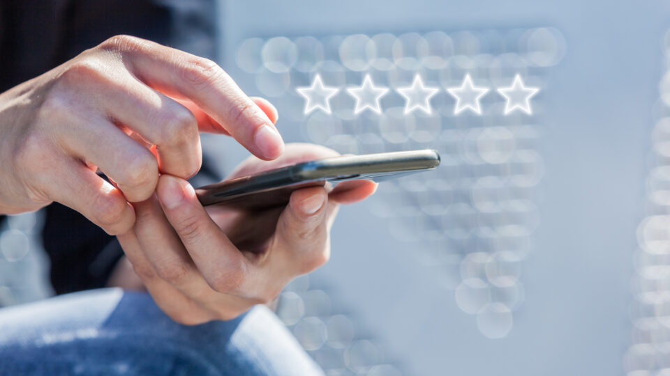 Customer Service Experience Performance Analysis. Close-up of Woman's Hand Holding a Smart Phone with Icon Five Star Symbol to Increase Rating of Company.